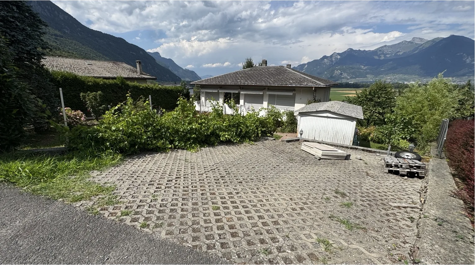 Cour pavée avec places de stationnement extérieures et vue sur les montagnes